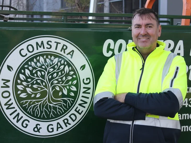 Neil Meredith, horticulturist at COMSTRA Mowing, beside the branded trailer