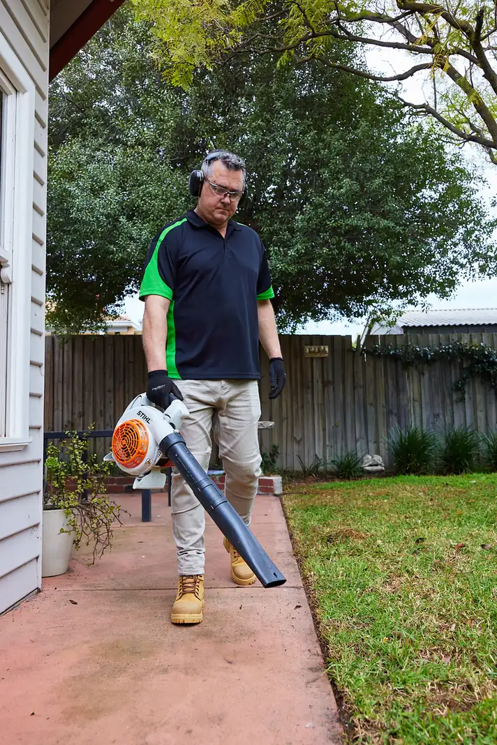 COMSTRA Mowing gardener leaf blowing a paved patio in a residential backyard in Avondale Heights