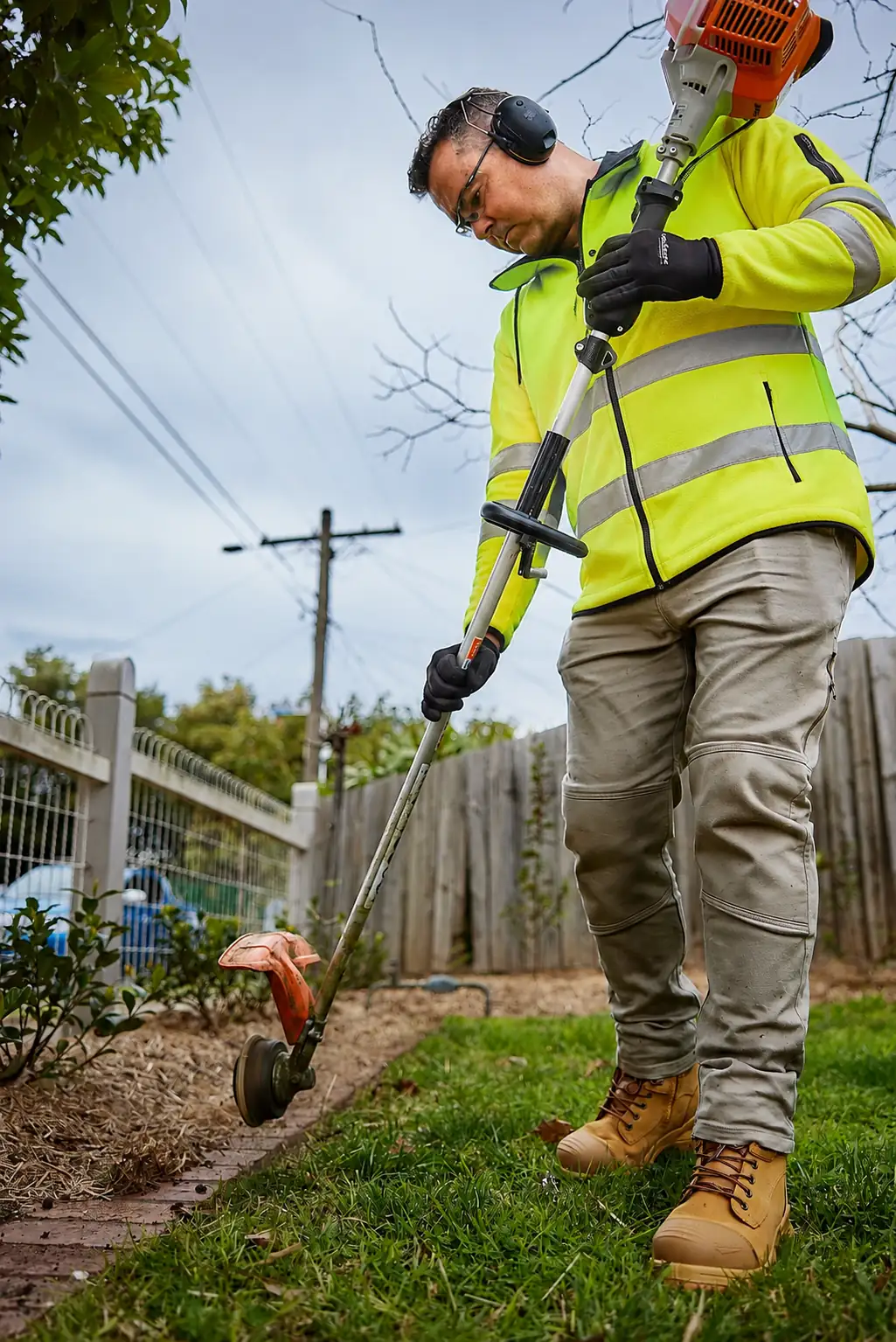 COMSTRA Mowing gardener line trimming the edge of a garden bed in Sunshine West